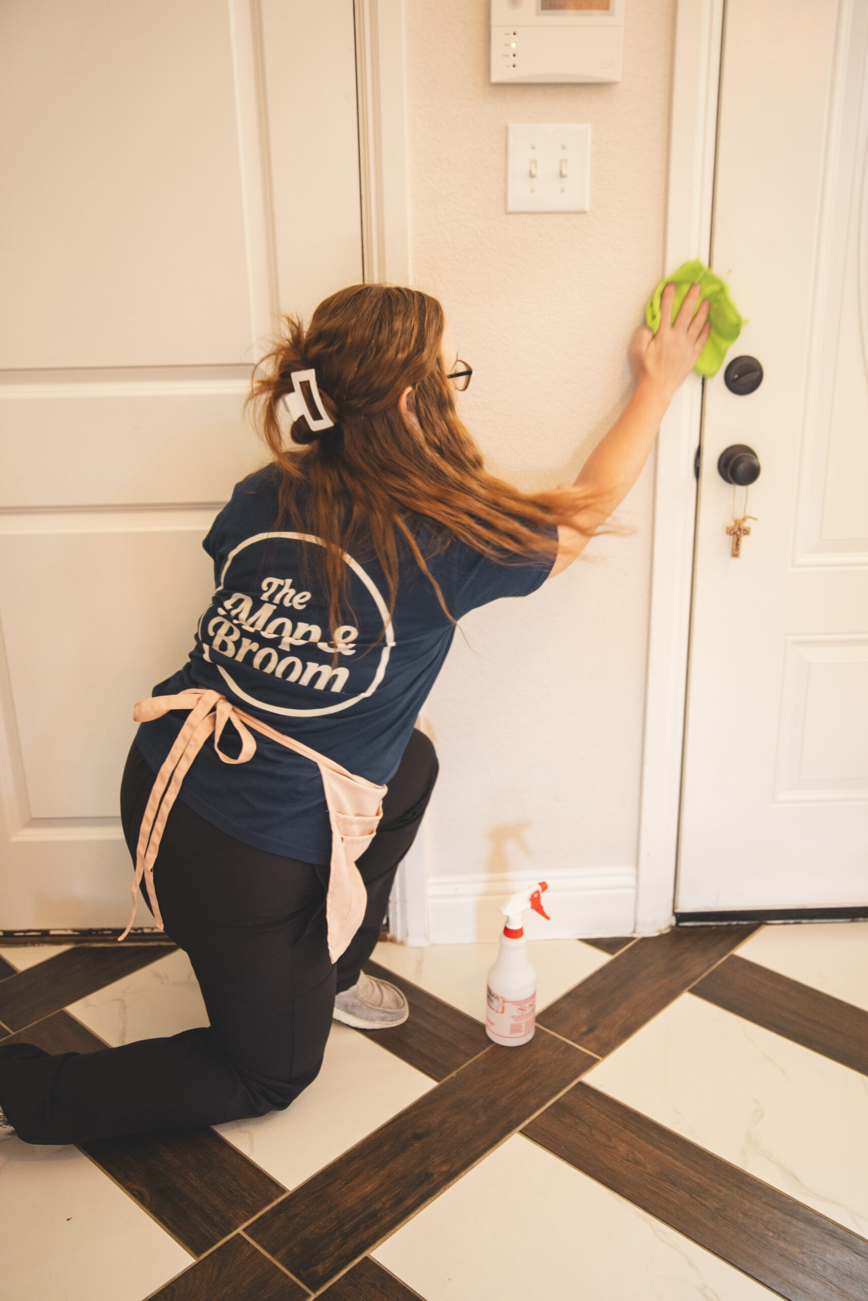 Professional maid services near me by The Mop & Broom, cleaning floors with spray and cloth